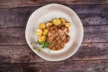 BBQ pork loin meat steak with potato. Dark background.