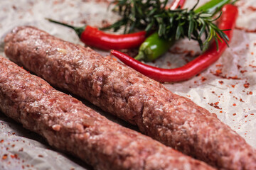 lyulya kebab close-up, meat dish for cooking in nature, barbecue lies on parchment light paper with spices and salt. Selective focus