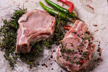 Raw fresh beef ribs eye steak on a light surface, parchment, before cooking. Seasoning for meat rib steak for eyes rosemary, coriander, pepper. Top view, flat lying.
