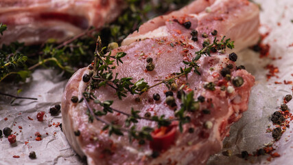 Raw fresh beef ribs eye steak on a light surface, parchment, before cooking. Seasoning for meat rib steak for eyes rosemary, coriander, pepper. Top view, flat lying.