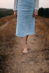 long denim skirt. a woman walks barefoot along the path. walking barefoot in the field.