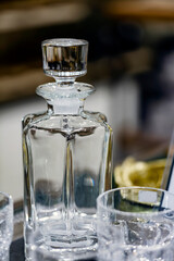 Elegant empty carafe and two glass on wooden table. Decanter in dark style. Blurred background, selective focus, shot with shallow depth of field. Table setting. holiday interior decor