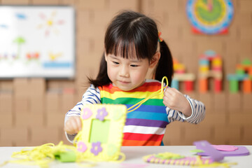 young girl sewing pad craft using plastic needle and yarn at home