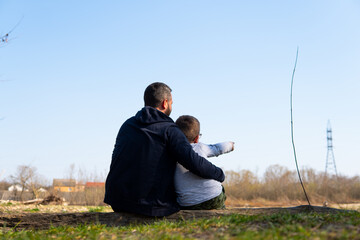 father with son sitting in nature