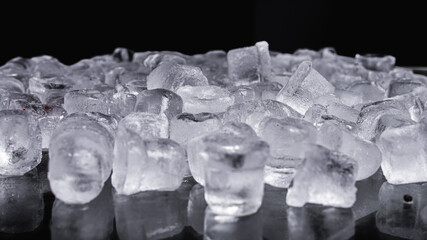 crushed ice scattered, diced, on a black background, ice for drinks. Close up view. Selective focus