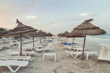empty Tunisian beach with old sun loungers and sun canopies
