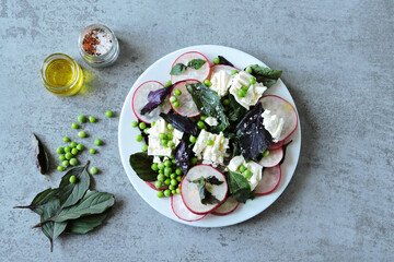 A healthy salad with fresh radishes, green peas and feta cheese. Healthy diet. Delicious fresh salad.