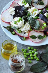 A healthy salad with fresh radishes, green peas and feta cheese. Healthy diet. Delicious fresh salad.