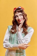 Young cute brunette woman with wavy hair. The hand touches the face. Pin-up style. Yellow background.