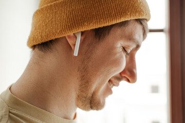 Obraz premium Close up young man traveler listening to music in AirPods in hotel room on summer vacation
