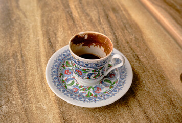 Traditional turkish coffee pot and dish with iznik tile gravures on the cup in cafe and wooden table.