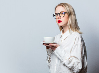 Portrait of beautiful blonde in white shirt with cup of coffee on white background