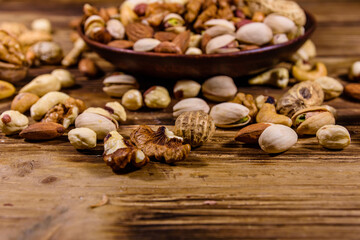 Various nuts (almond, cashew, hazelnut, pistachio, walnut) in ceramic plate on a wooden table. Vegetarian meal. Healthy eating concept