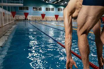 Strong Caucasian man prepares to make a jump into the water in a swimming pool. Copy space