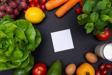 Biała karteczka na czarnym tle, otoczona warzywami i owocami z miejscem na tekst o diecie, zdrowym odżywianiu, nawykach żywieniowych. Flat lay, mockup