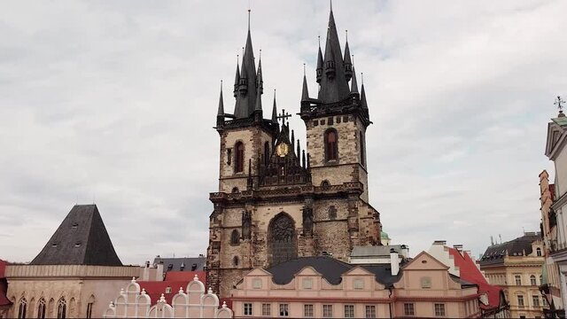 Pigeons fly over empty main old town square of Prague, on background of gothic costel.
