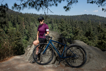 Obraz premium mujer latina con bicicleta descansando en el bosque, con un paisaje de arboles al fondo. Concepto deporte al aire libre