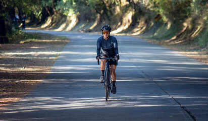 Mujer latina montando en bicicleta en una carretera en medio del bosque. Concepto deporte al aire libre