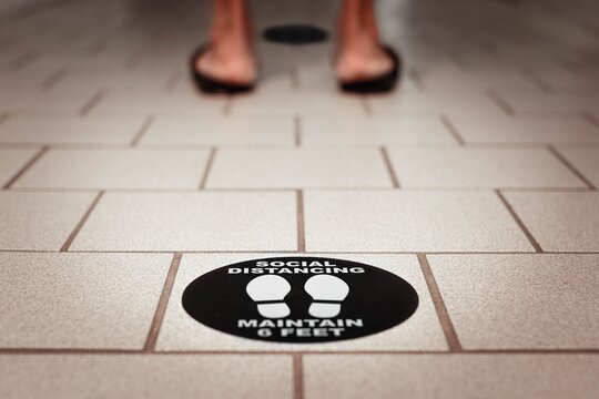 People standing in line on a 6 feet mark on the floor. Covid safety.