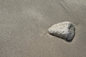 Fototapeta na wymiar 砂浜の砂に埋もれる小石 