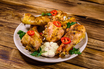 Baked chicken legs with parsley, garlic and sliced red hot pepper in a plate