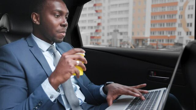 African american businessman rides in car with laptop