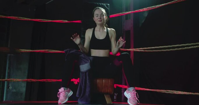 Boxer girl getting ready for training. The boxer warms up in the ring, rope, plank, stretching, warms up the muscles. A boxer hits punching bag in the ring. Motivational sports video.