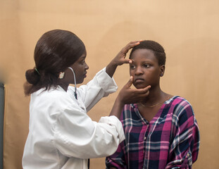 Fototapeta premium African female nurse , doctor or medical specialist checking a lady patient for health reasons, and also has stethoscope with her