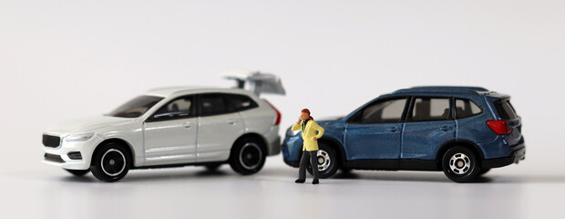 Two miniature cars collided with Miniature man calling. Concepts about car accidents and miniature people.
