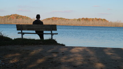 person sitting on a bench at the lake
