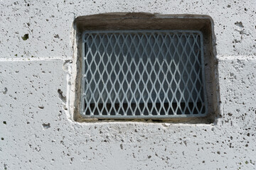 metal screen over a vent in a concrete wall