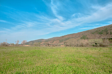 Agricultural field in Karacabey Bursa with small hill and blue sky background.