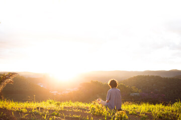 Young man sitting on the top of a mountain and looking at the sunset and having thoughts and reflections. 