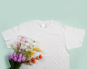 plain white t-shirt on green background. T-shirts made of cotton are very comfortable to use when the weather is sunny. This plain t-shirt goes great with any colored trousers. Mockup for your ad.