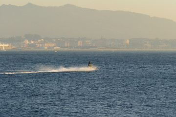 jet ski furrows the sea with the city in the background