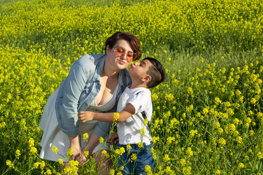 mexican mom and son playing on picnic in field full of flowers in summer