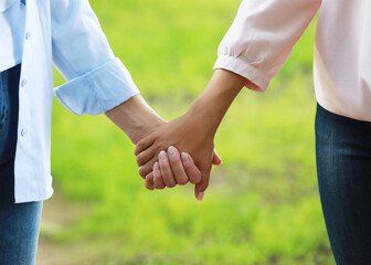 Elderly Mother holding a hand of her adult daughter in summer day outdoors