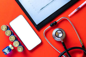 Medical equipment. Doctor stethoscope, healthcare charts, syringe with needle and black smartphone with blank screen on hospital red background. For design application, website project.