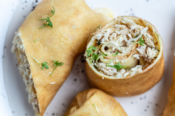 thin pancakes or crepes stuffed chicken meat served on a white plate, place for text, Food recipe background. Close up