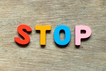 Color alphabet letter in word stop on wood background