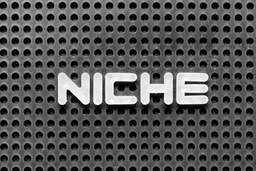 White alphabet letter in word niche on black pegboard background © bankrx