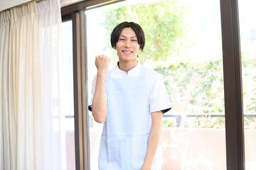 ガッツポーズをするエプロン姿の若い男性