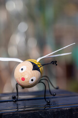 Bee made of wood with happy smiling face in unusual rainy spring weather and copy space for free text 