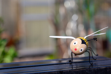 wooden Bee figure with happy, smiling face in unusual spring weather with rain and copyspace for text on left side