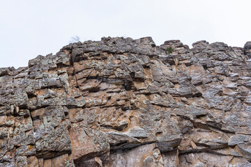The surface of the rocky ridge in winter. Plots of white snow, sky. Sharp stone ledges.