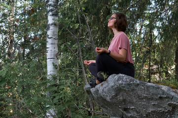 Relaxed touristic woman sit on a stone in mountain forest