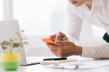 Young Asian businessman using smartphone and laptop at office
