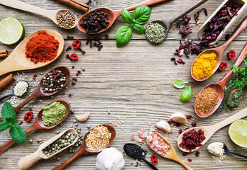 A selection of various colorful spices on a wooden table in  spoons