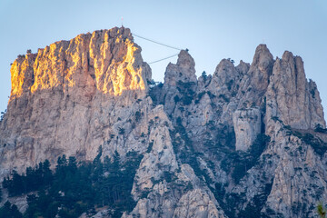 High mountains with forested slopes and peaks on blue sky background