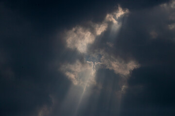 Naklejka na ściany i meble Sun rays of shining down with light and dark clouds.